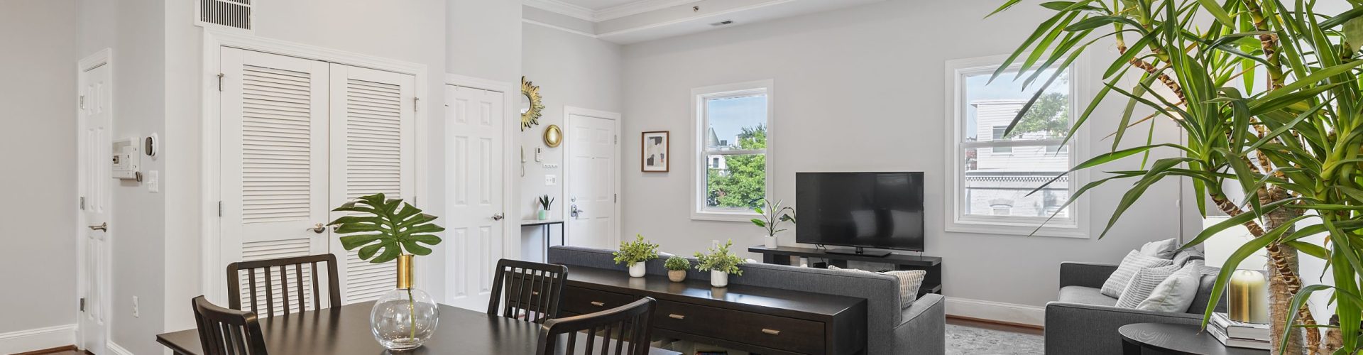 Gallery Image – Modern Living & Dining Space with Light | Prismatic Home Photography Contemporary open-concept living and dining space with neutral tones, hardwood floors, indoor plants, and natural light from multiple windows.